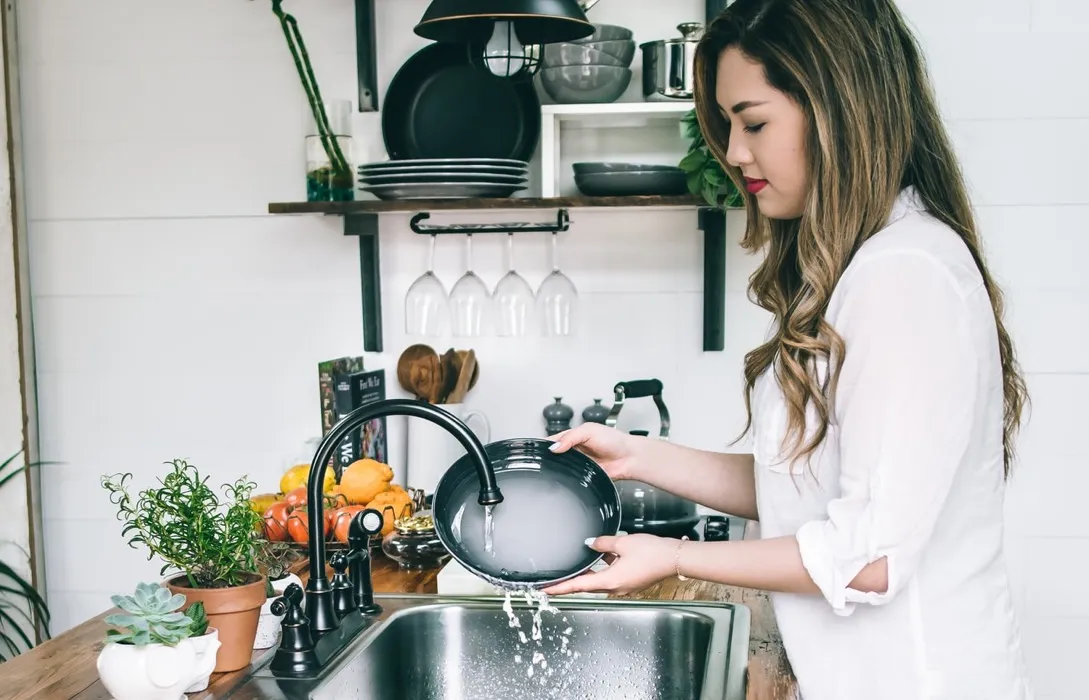 lady washing at sink dish plant kitchen water